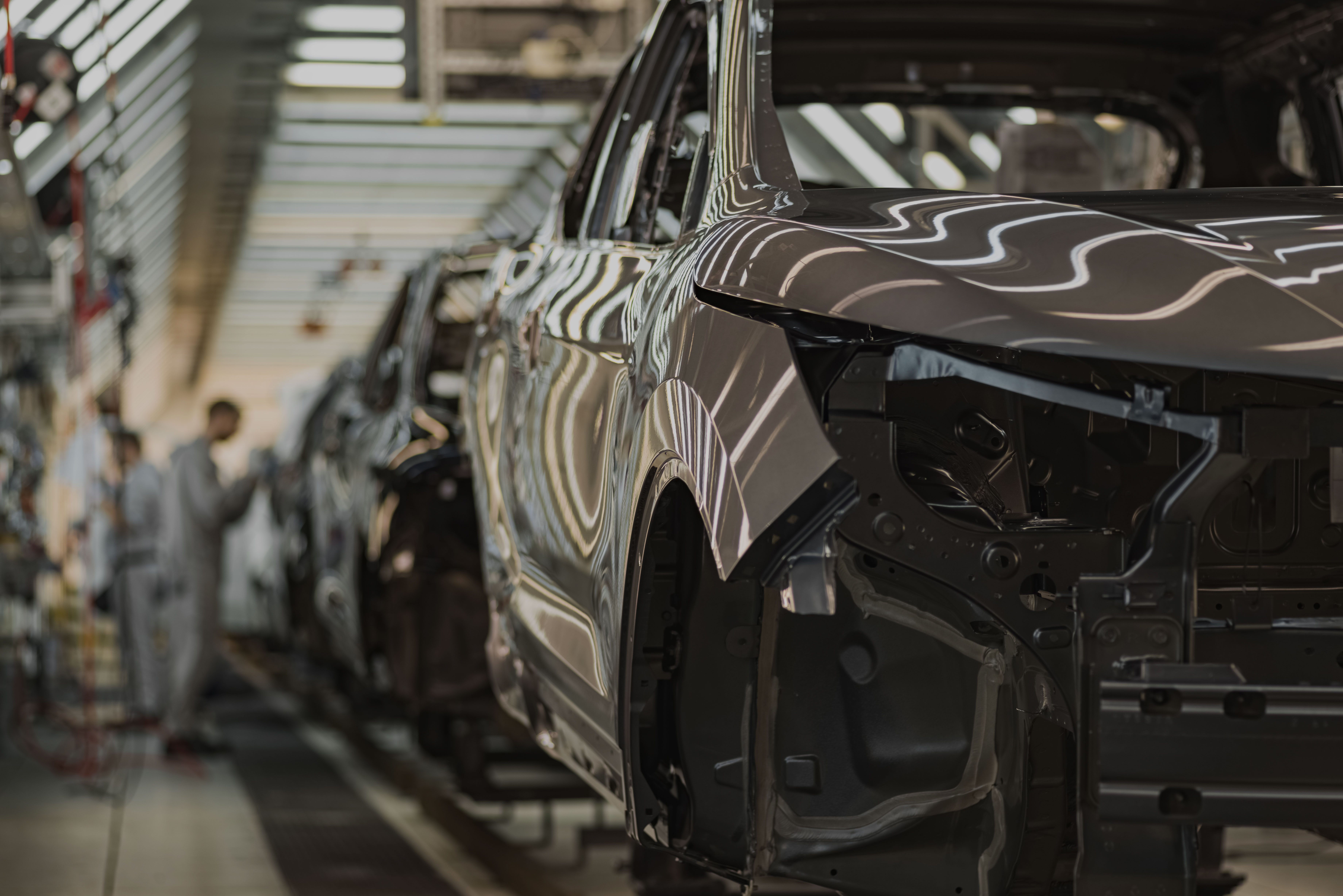 Close-up of a modern car body in an automotive plant, symbolising safety and reliability services for automotive systems.