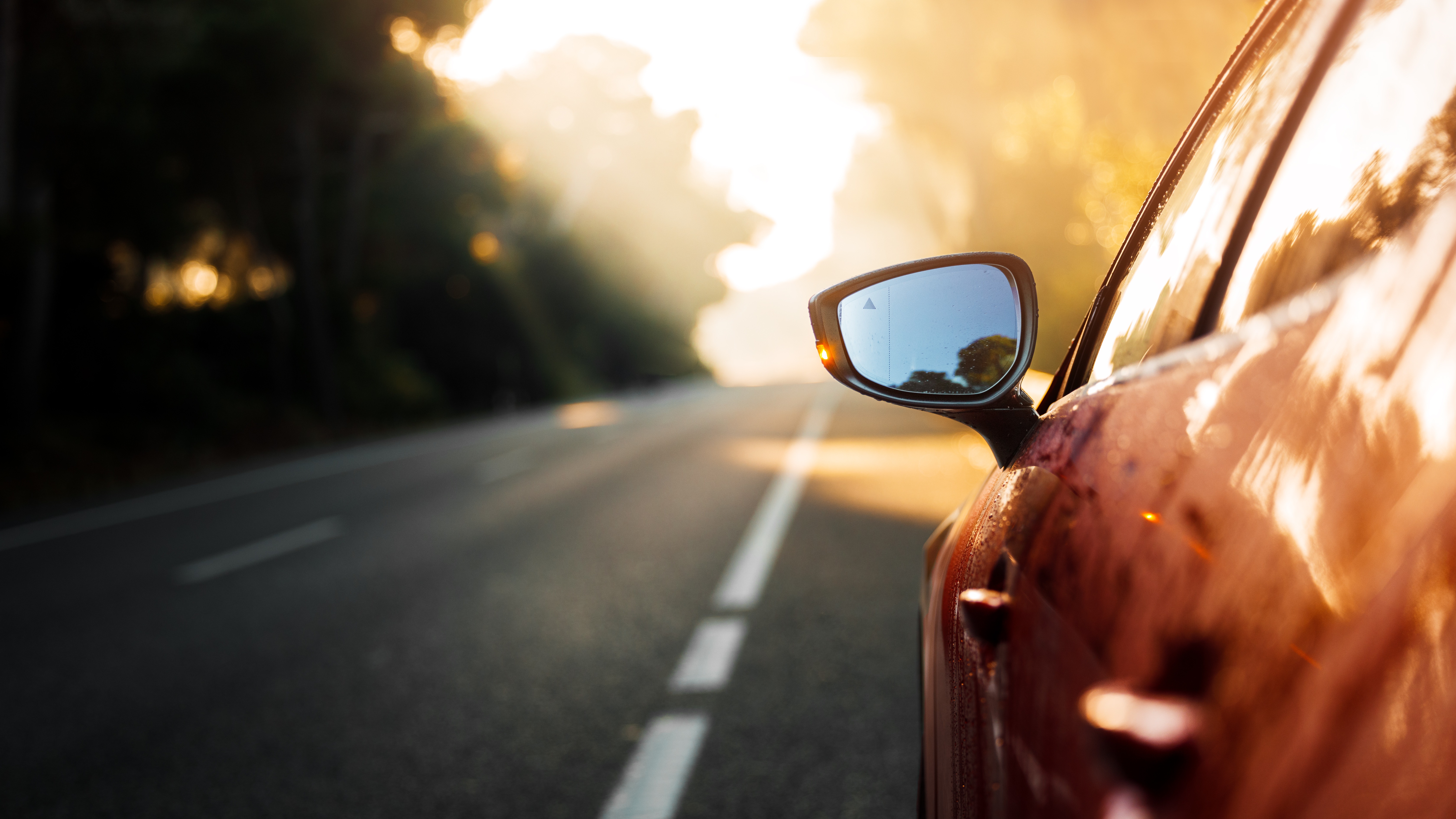 Close-up of a car side mirror on a sunlit road, symbolising forward-looking automotive software and process improvement