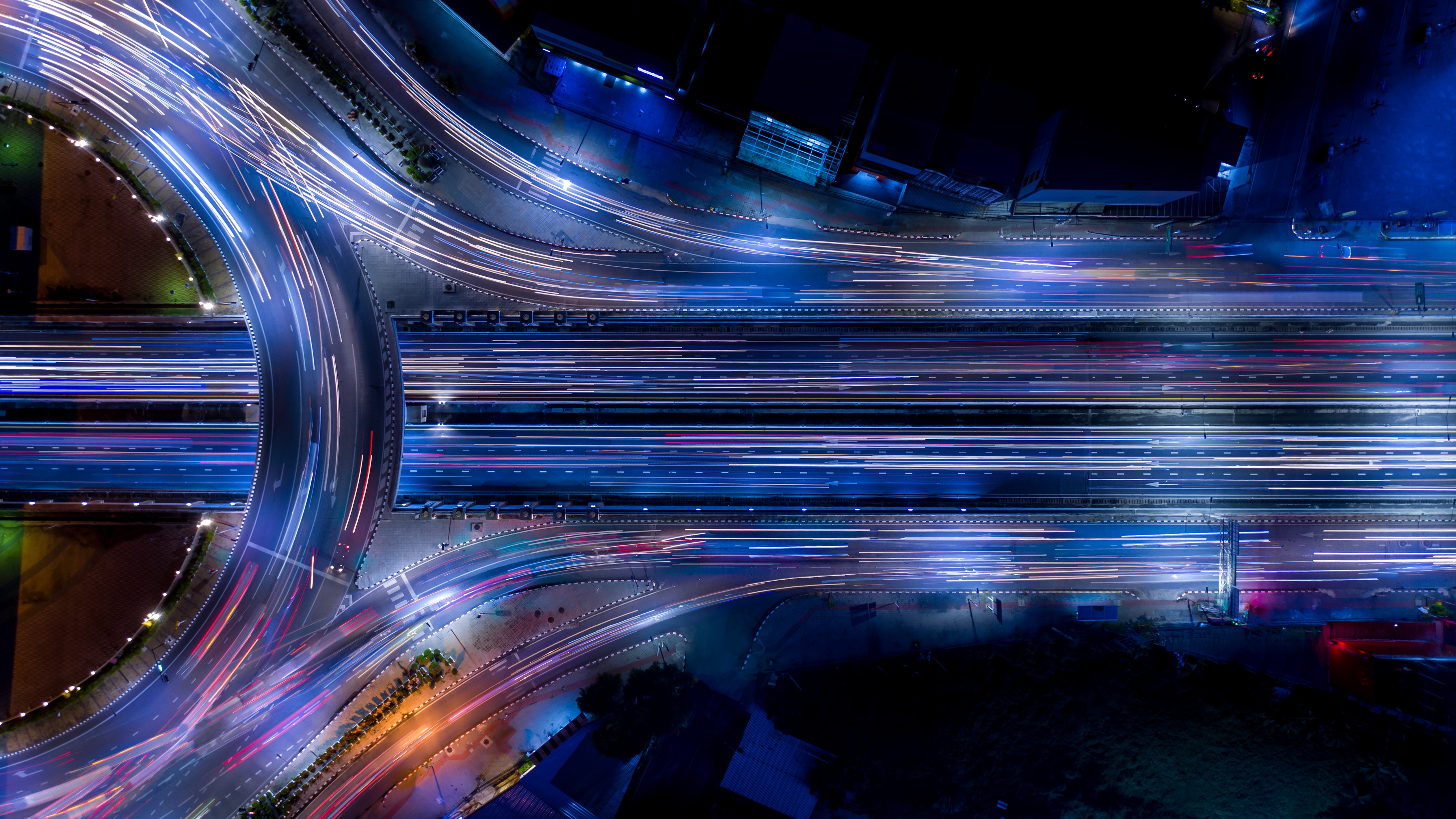 Overhead view of multilane highway at night with light trails, illustrating fast-moving automotive development and complex system interactions