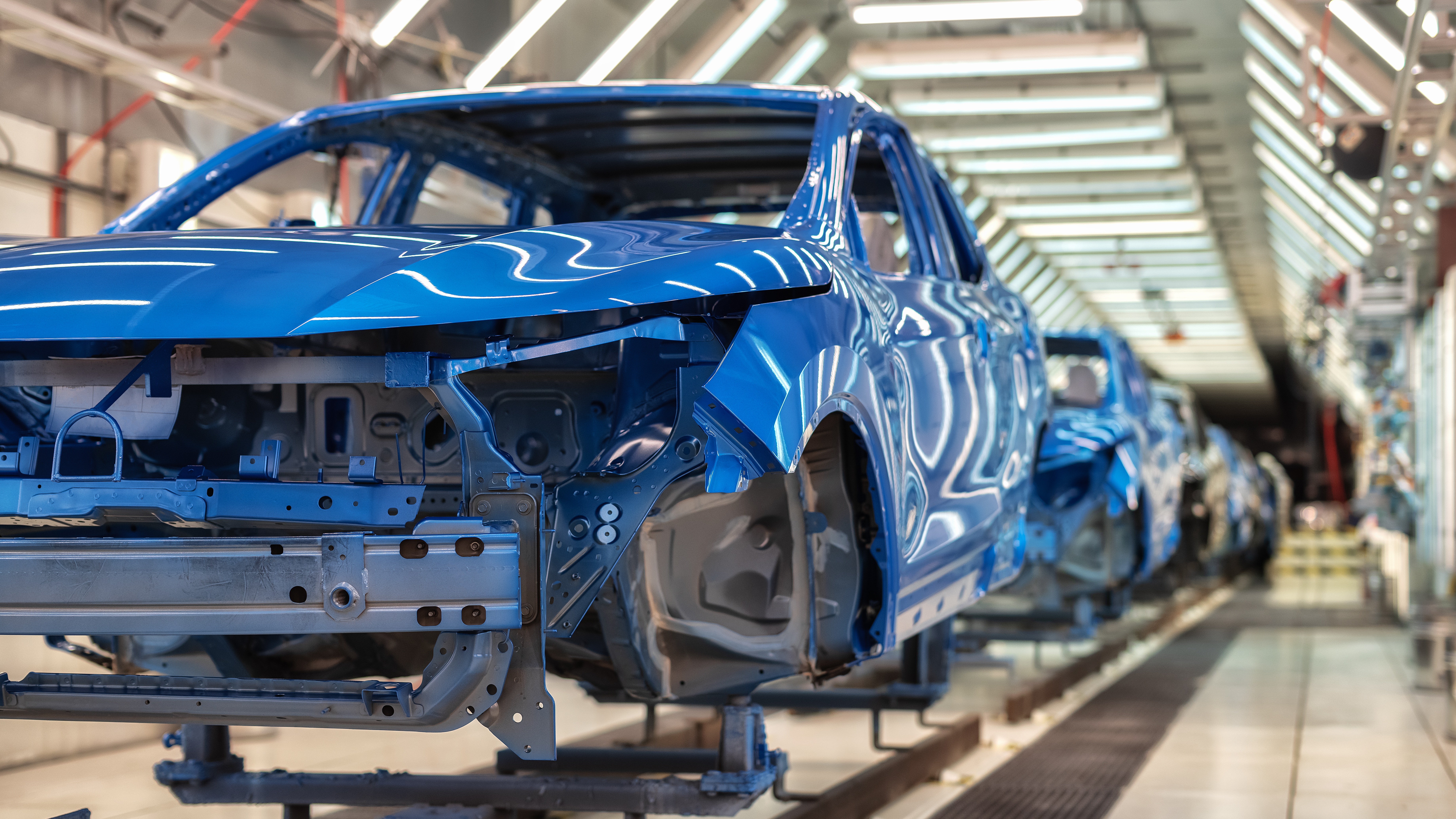 lue car bodies on an automotive production line, representing early-stage product risk assessment in vehicle development