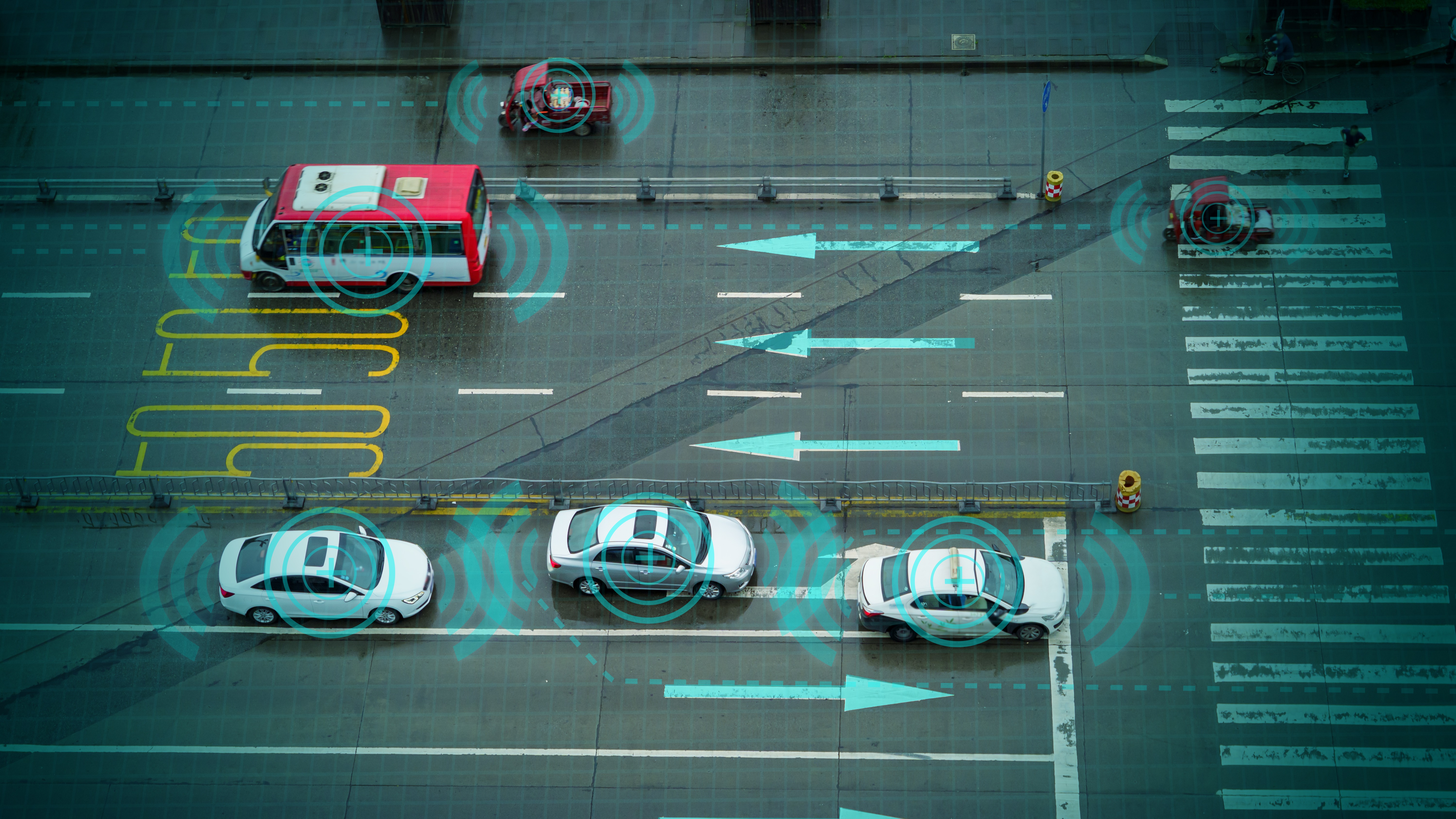 Overhead view of multiple lanes of city traffic with digital sensor overlays illustrating connected and autonomous vehicle safety simulation
