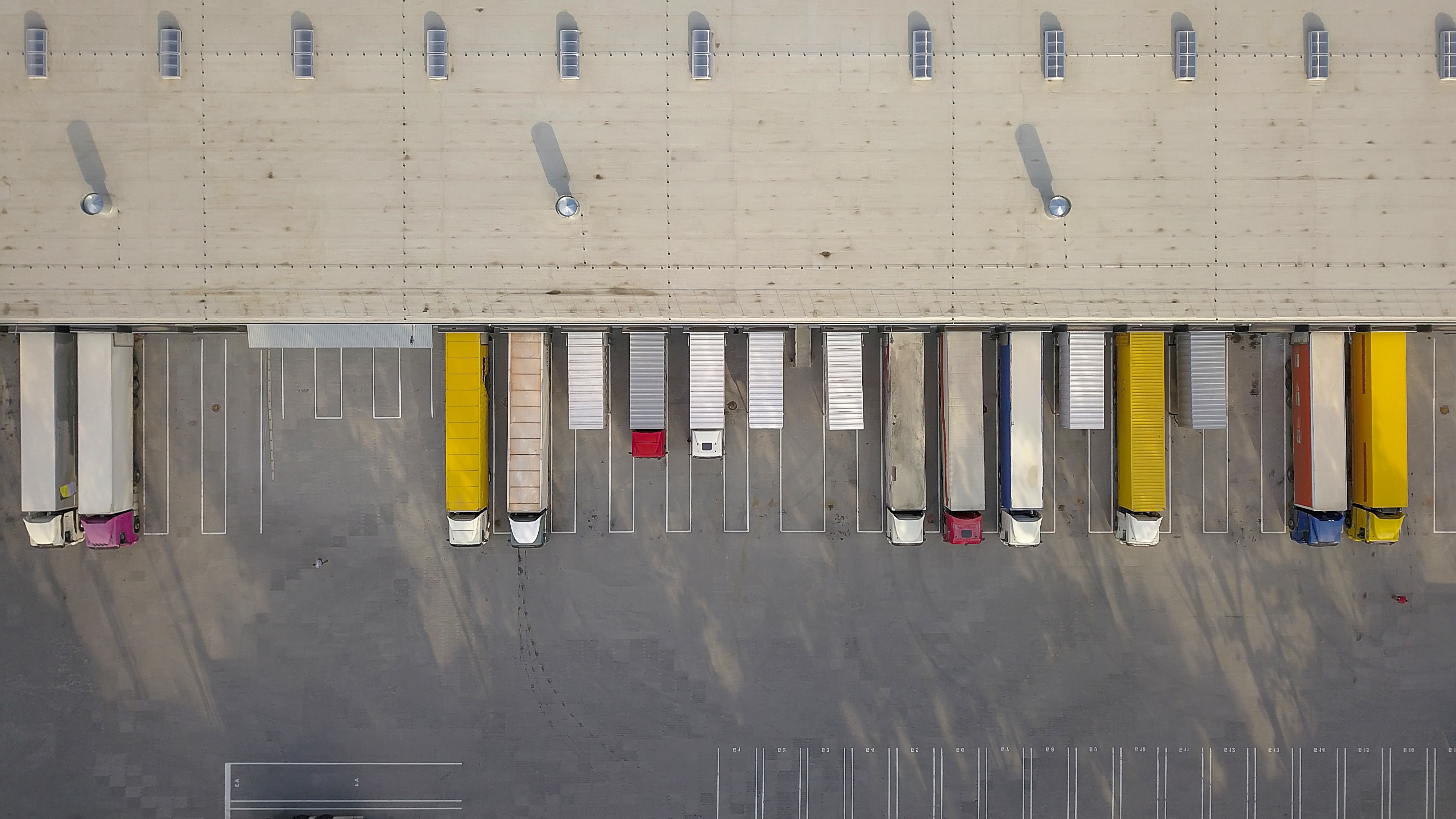 Aerial view of a warehouse floor with organized pallets and automated pathways, illustrating supply chain operations and performance monitoring.