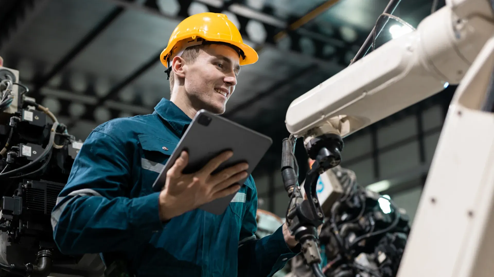 Engineer assessing automated machinery with a tablet in a low-carbon manufacturing environment, illustrating operational data collection for carbon neutrality verification