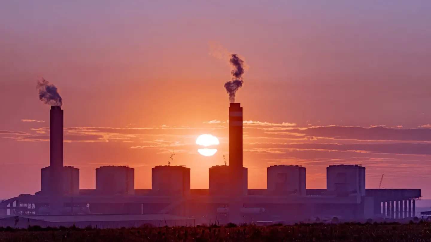 Industrial facility with smokestack at sunset symbolizing hard-to-abate sector emissions and the need for strategic decarbonization planning