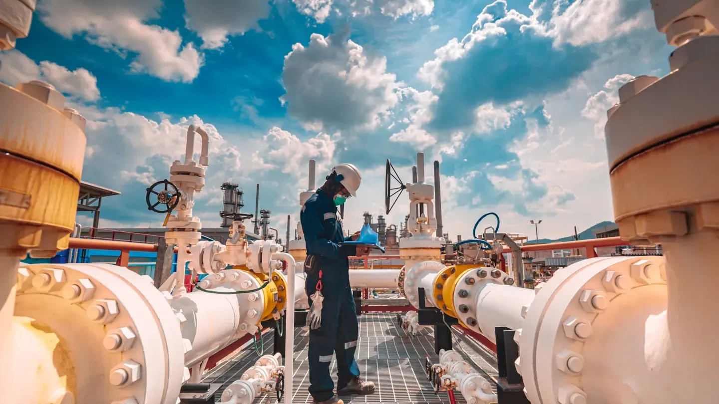 Engineer inspecting industrial pipelines at a petrochemical facility, representing supply chain emissions mapping and decarbonization analysis