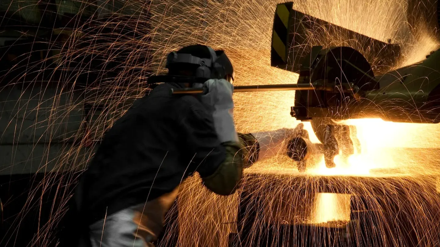 Steel manufacturing operation with sparks during metal cutting, illustrating verification of green steel practices and compliance with sustainability standards