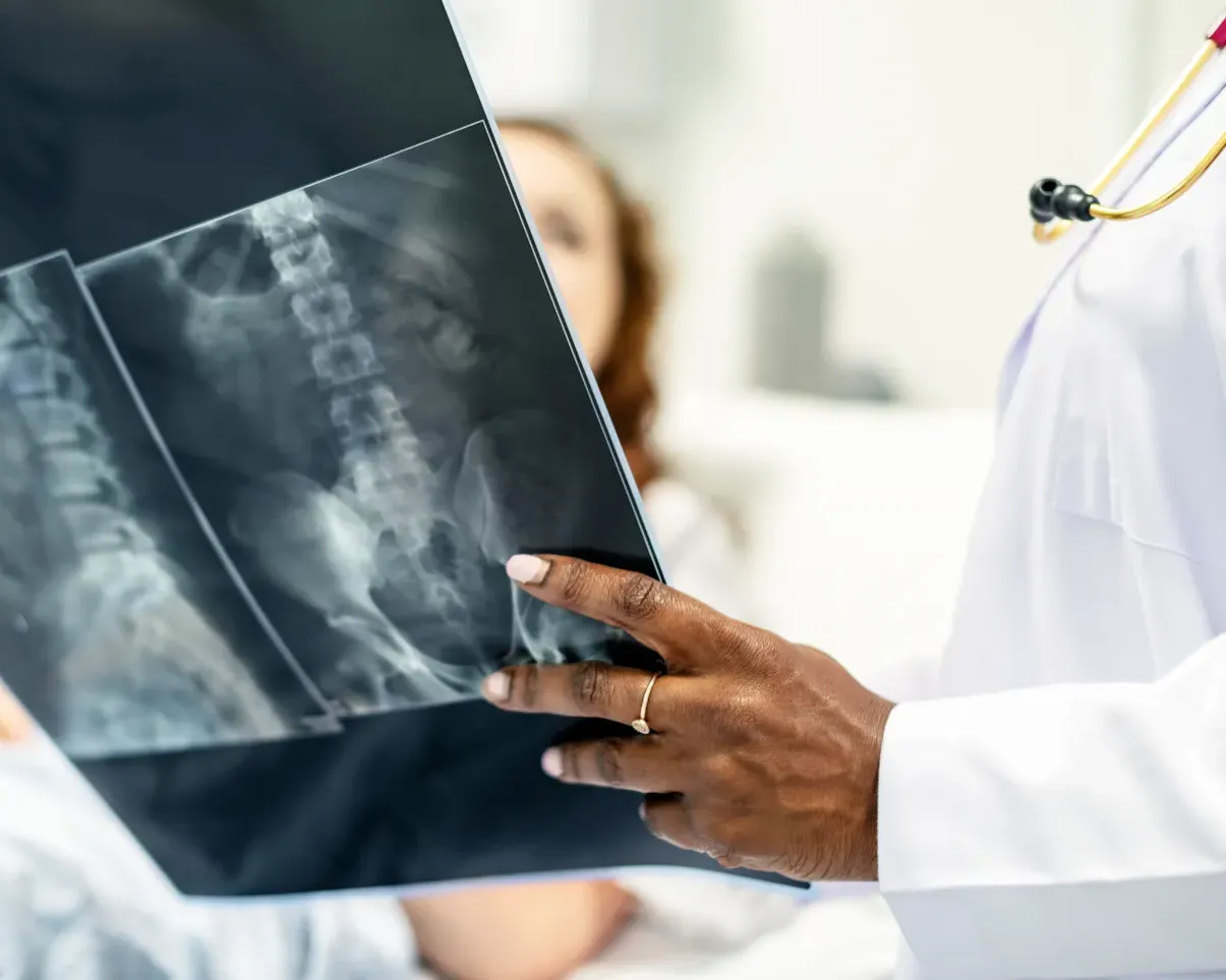 Orthopaedic specialist reviewing a spine X-ray with a patient, reflecting DNV’s evidence-based approach to orthopaedic and spine care excellence