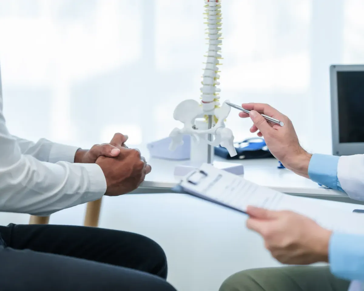 Clinician reviewing a spine model with a patient, illustrating evidence-based education and patient-centred decision-making in advanced spine surgery care