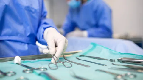 A sterile processing technician preparing surgical instruments in a controlled environment, symbolizing precision, patient safety, and quality assurance.