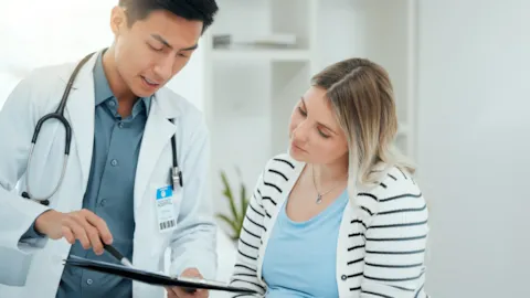 Healthcare professional consulting a patient using a digital tablet, representing collaboration, safety, and quality in clinic care.