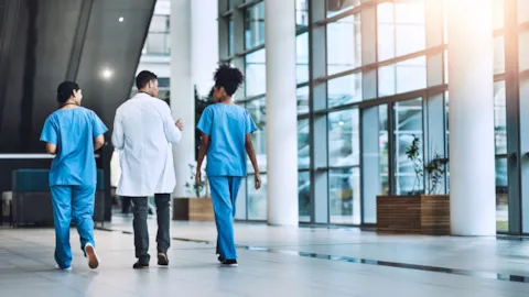 Hospital staff in surgical attire assisting a patient on a stretcher, symbolizing teamwork, safety, and quality care in an acute hospital setting.
