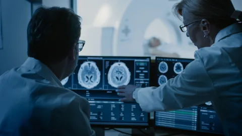Two healthcare professionals reviewing brain scan images, representing coordinated stroke care and evidence-based decision-making in a hospital setting.