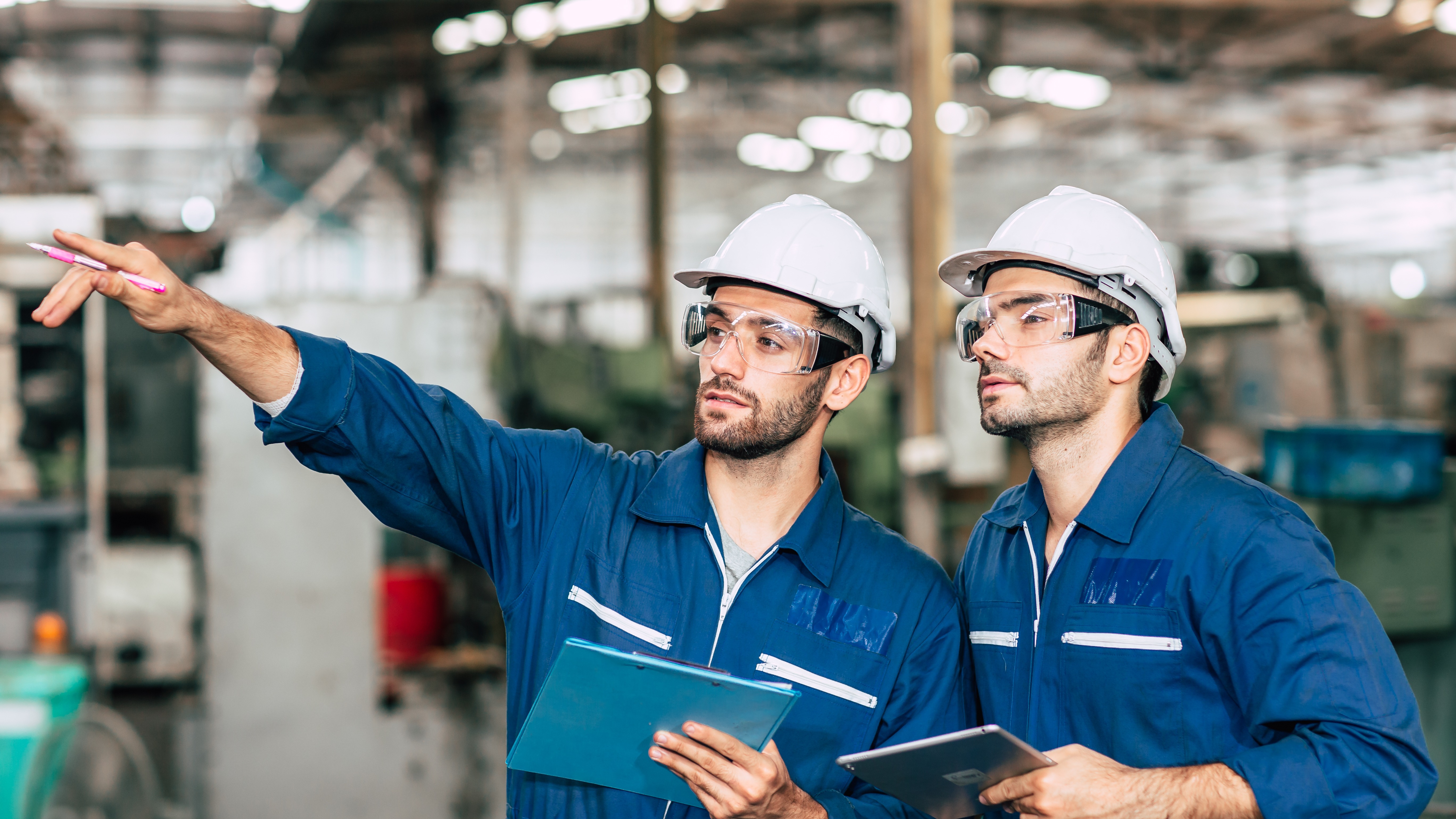 Team of industrial engineers in safety gear discussing machinery compliance in a modern manufacturing facility