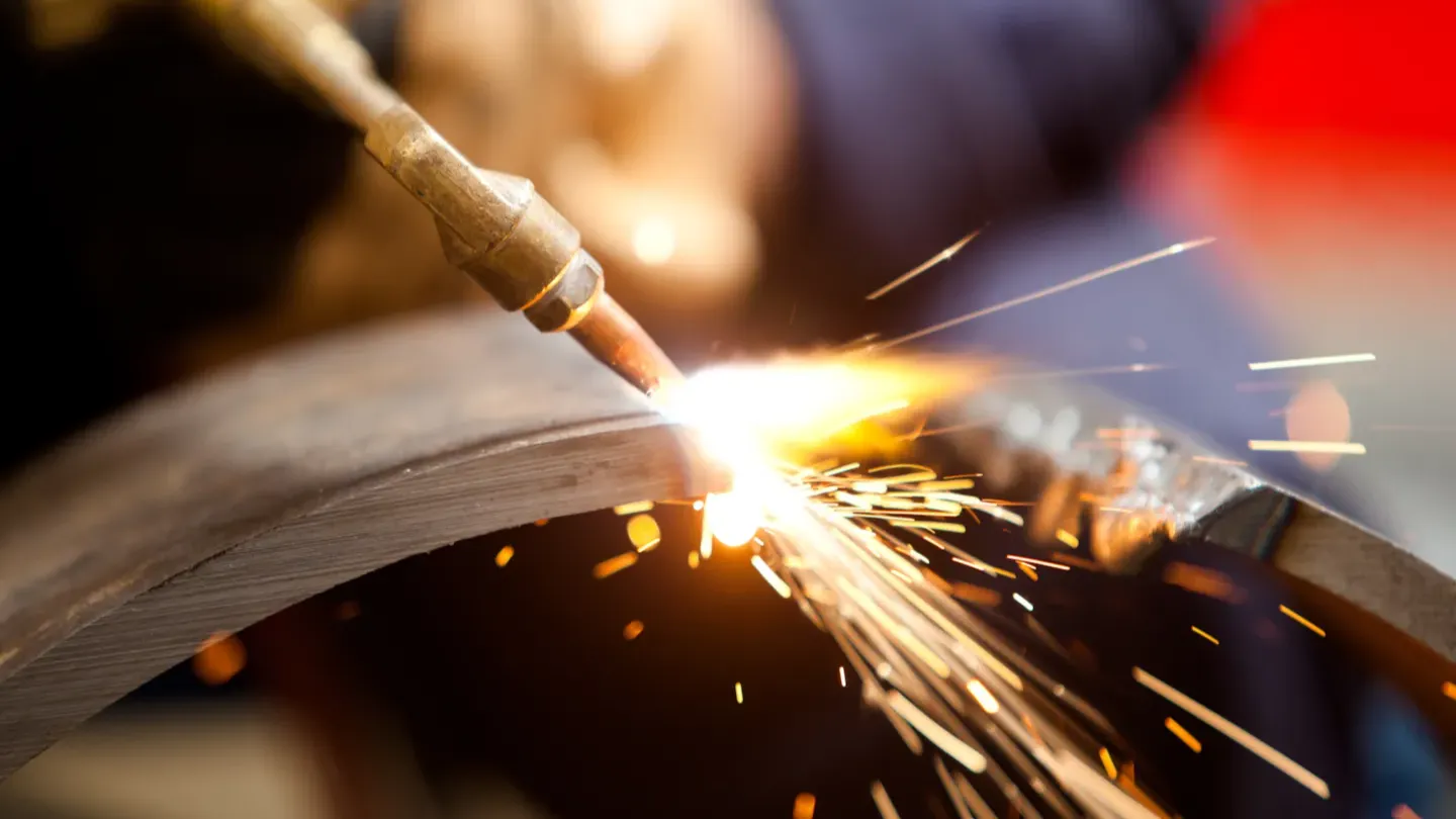 Close-up of metal grinding with sparks, representing quality control and compliance assessment for welding consumables and materials