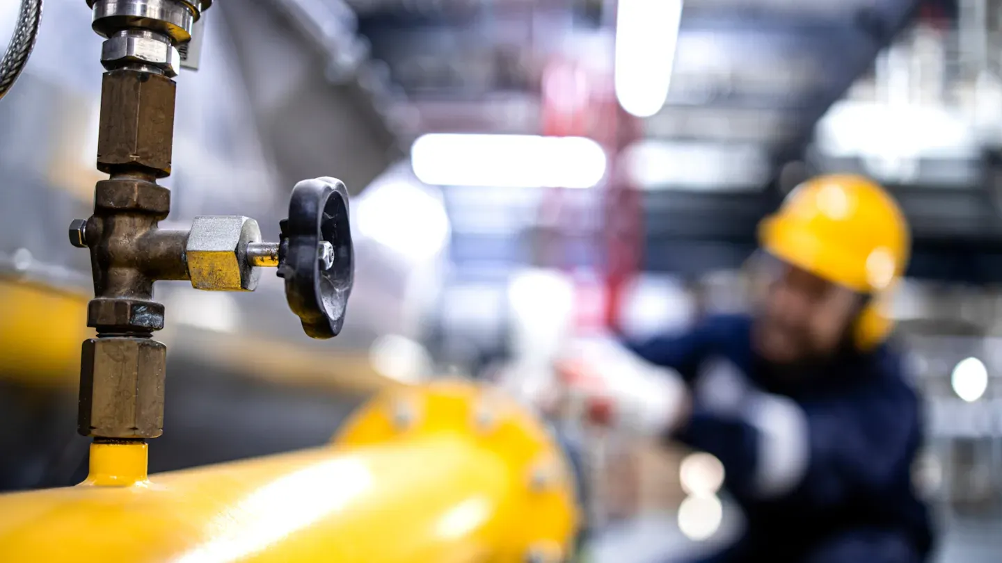 Inspector examining pressure equipment valves and connections in an industrial facility, representing PED and PESR compliance verification