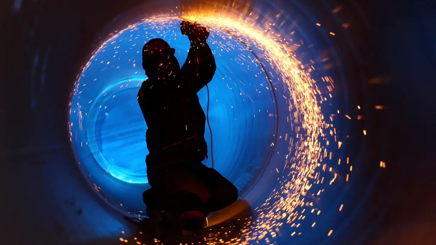 Welder working inside a circular steel structure, demonstrating certified welding competence and compliance with EN ISO and ASME standards