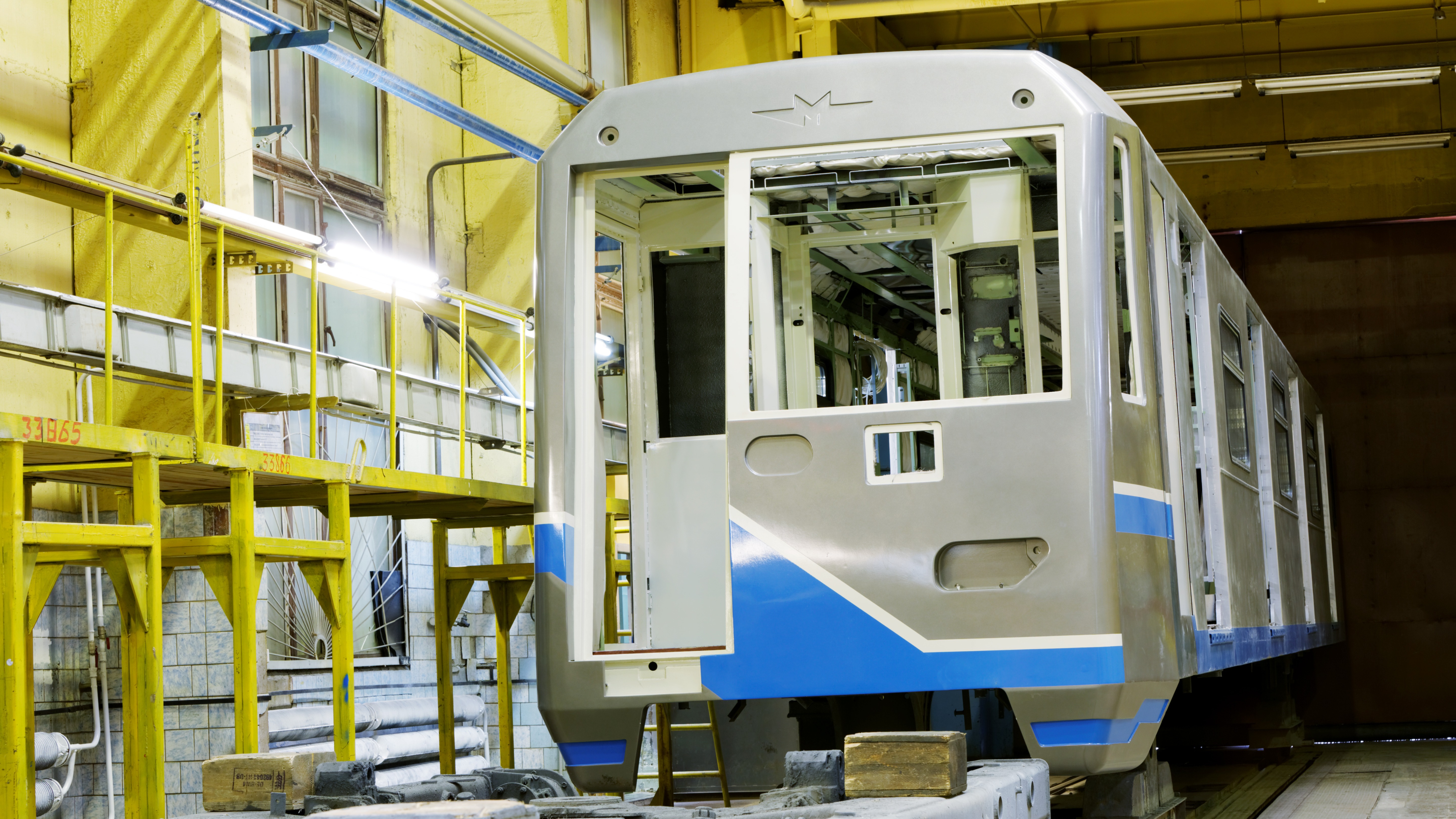 Modern railway vehicle in a manufacturing facility undergoing welding and assembly
