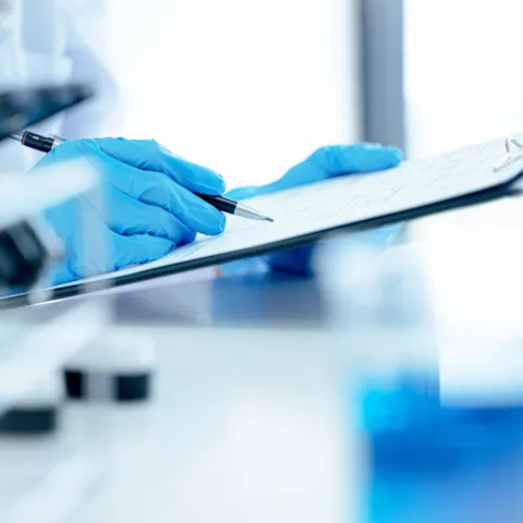 Laboratory professional wearing protective gloves reviewing certification documents, representing quality assurance and regulatory compliance for in vitro diagnostic devices.