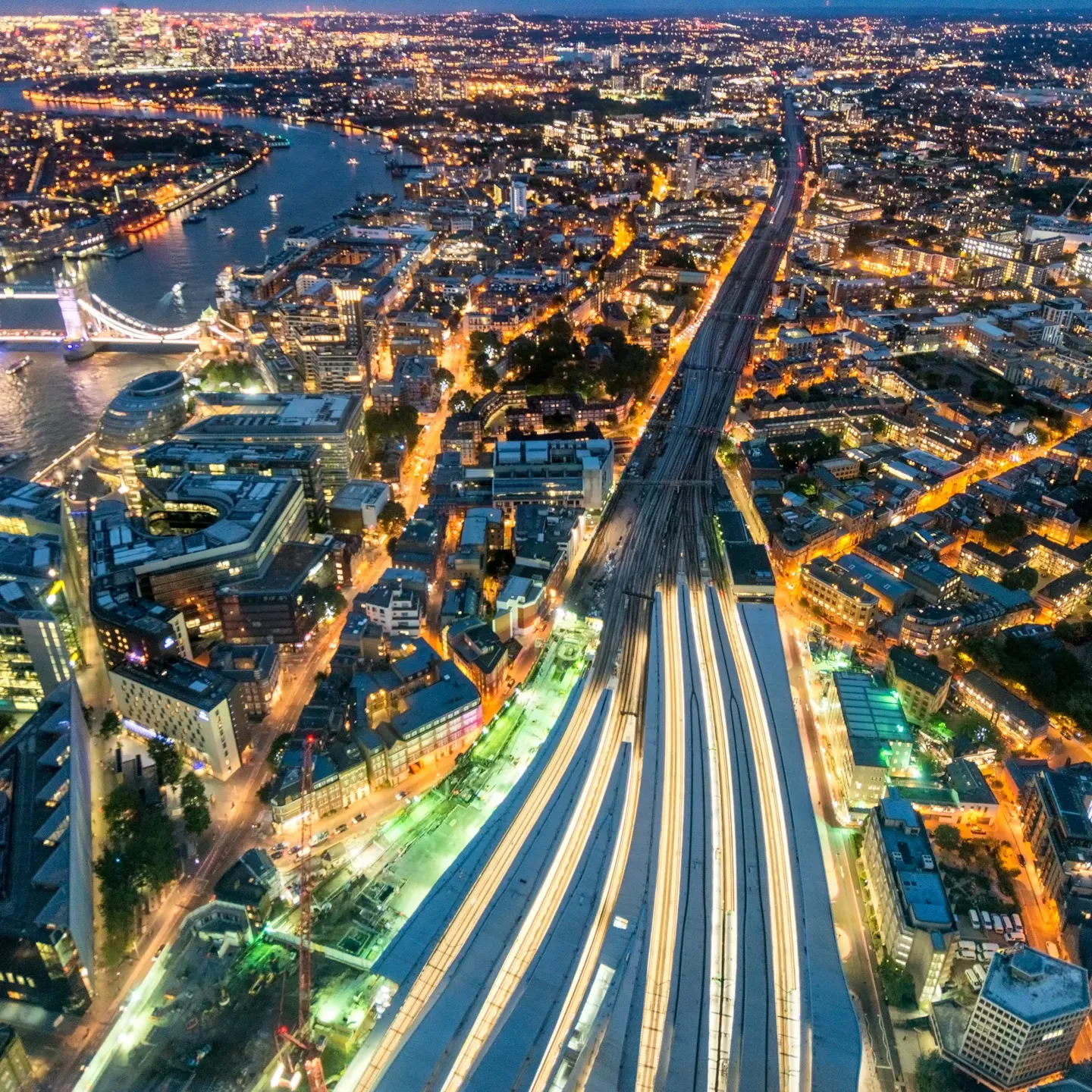 Aerial view of an urban railway network at night, illustrating complex rail infrastructure and operational environments