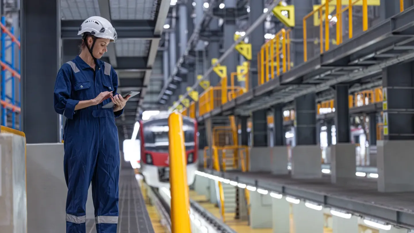 Rail technician inspecting digital control systems inside a modern railway operations facility