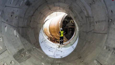Worker inspecting critical rail tunnel infrastructure, representing cybersecurity resilience and protection across railway environments