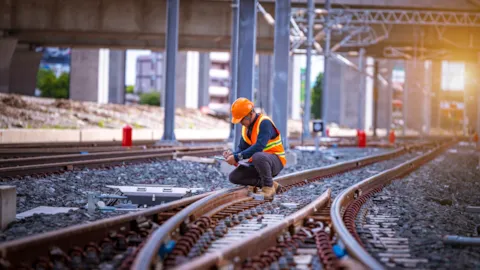 Rail safety engineer inspecting railway tracks and switches at a train yard, ensuring system reliability and safe infrastructure performance.