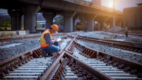 Rail inspector reviewing track components during maintenance work, ensuring compliance and operational safety in railway infrastructure.