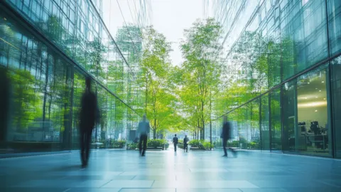 A modern glass financial district surrounded by greenery, symbolizing sustainable finance and ESG-aligned investment.
